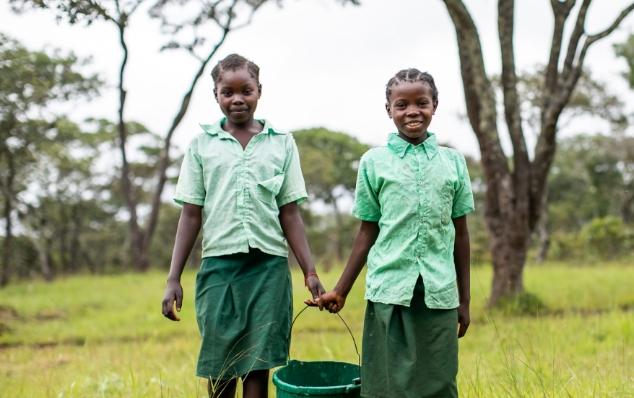 笑顔でバケツに水を入れる少女
